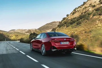 Vista dinámica del BMW Serie 5 mostrando su trasera y perfil lateral en carretera.