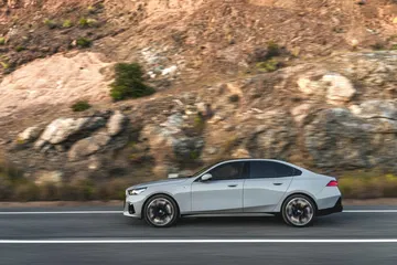 Vista dinámica de un BMW Serie 5 en carretera, enfatizando su diseño lateral.