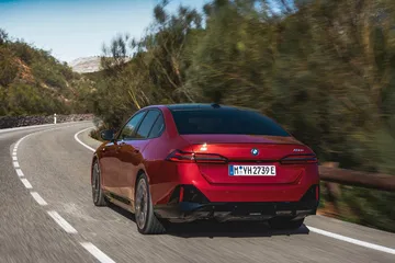 Vista trasera y lateral de un BMW Serie 5 en curva, destacando su diseño deportivo
