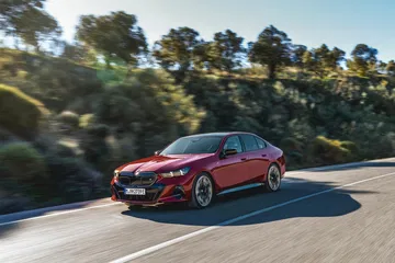 Vista dinámica de un BMW Serie 5 rojo circulando por carretera.