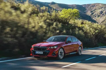 BMW Serie 5 en color rojo circulando por carretera serpenteante, destaca su diseño dinámico.