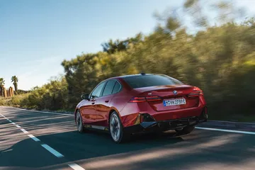 Vista dinámica trasera y lateral del BMW Serie 5 en carretera.