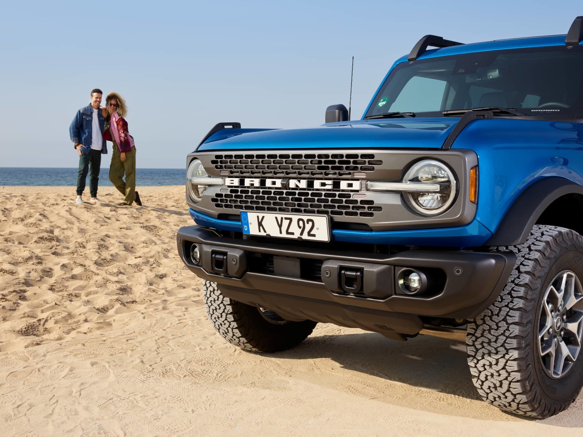 Vista lateral y delantera del Ford Bronco en color azul frente a la playa.