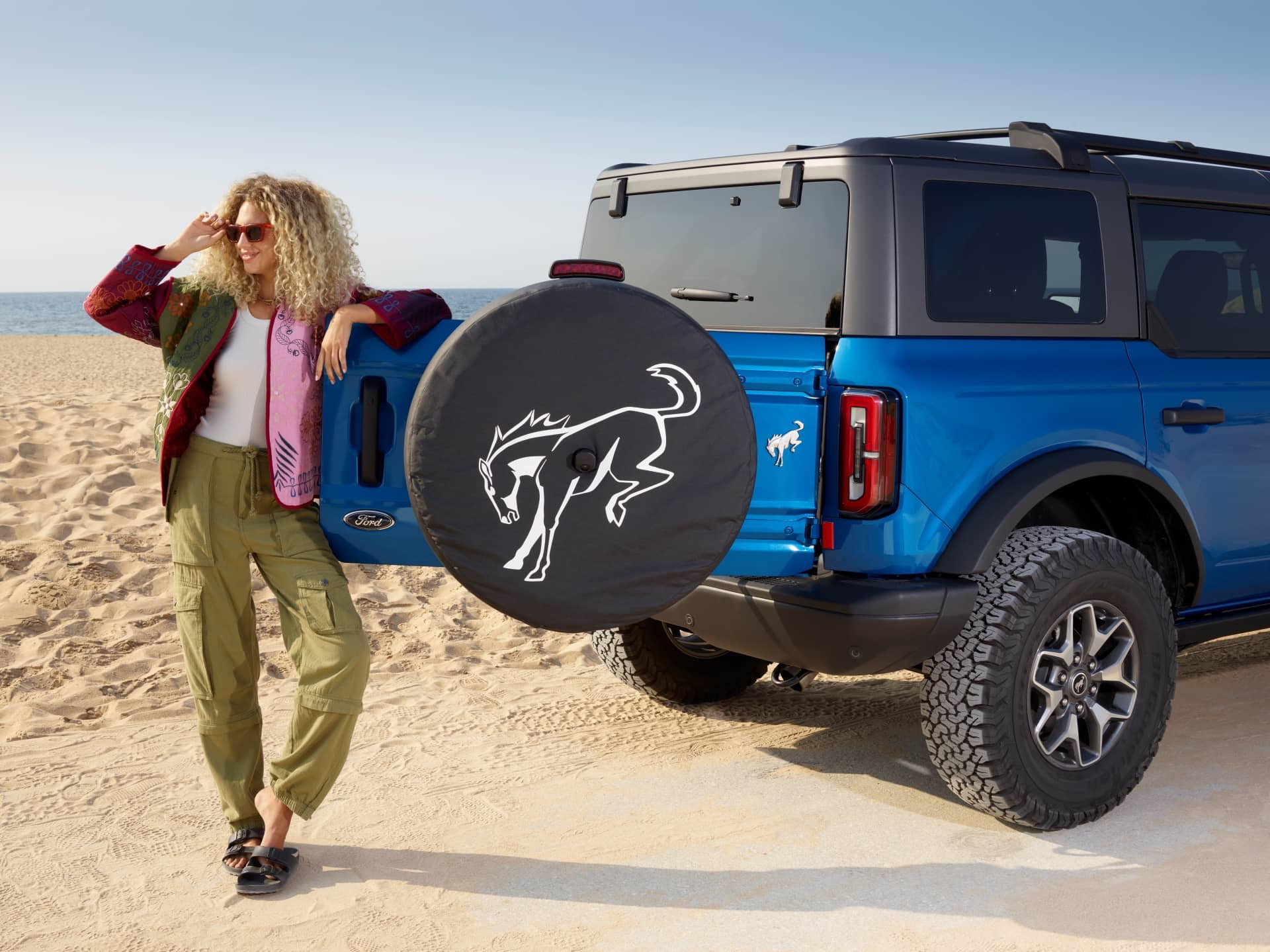 Vista de un Ford Bronco azul en la playa, mostrando su robustez y estilo.