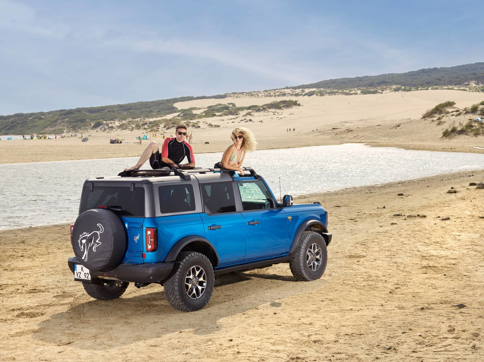 Vista lateral del Ford Bronco en un entorno de playa, destacando su línea y color vibrante.