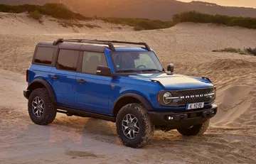 Ford Bronco azul superando terreno abrupto, mostrando capacidad off-road.