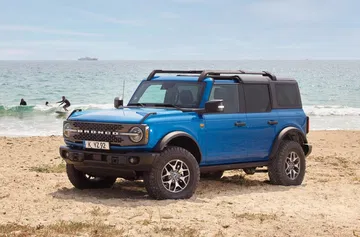 Vista lateral del Ford Bronco en la playa, resaltando su diseño robusto y aventurero.