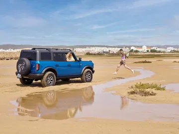 Ford Bronco en acción, superando obstáculos en un entorno arenoso.