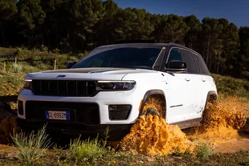 Vista lateral y frontal del Jeep Grand Cherokee en terreno agreste