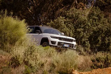 Vista lateral del Jeep Grand Cherokee en un entorno todoterreno.