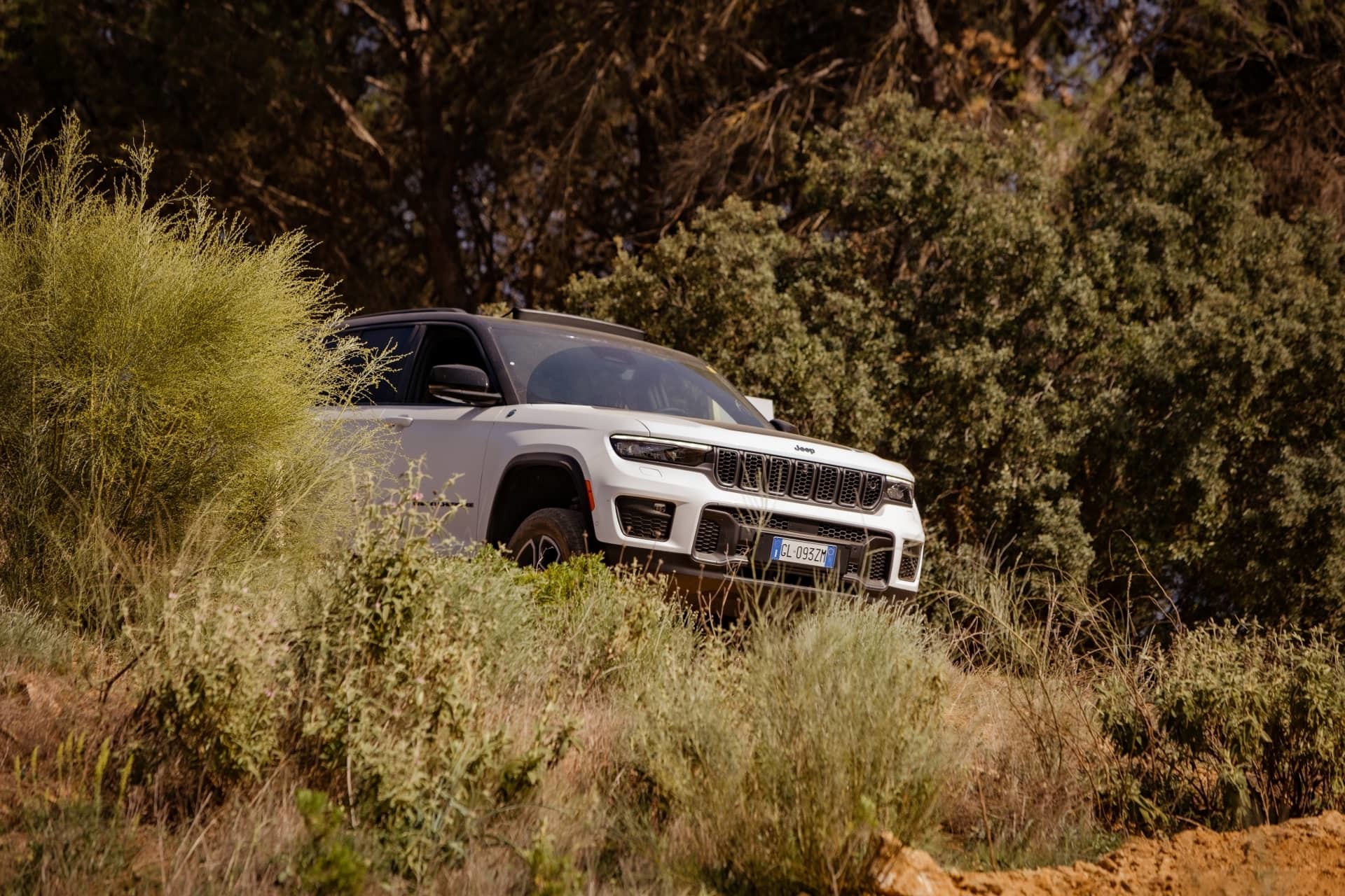 Vista lateral del Jeep Grand Cherokee en un entorno todoterreno.