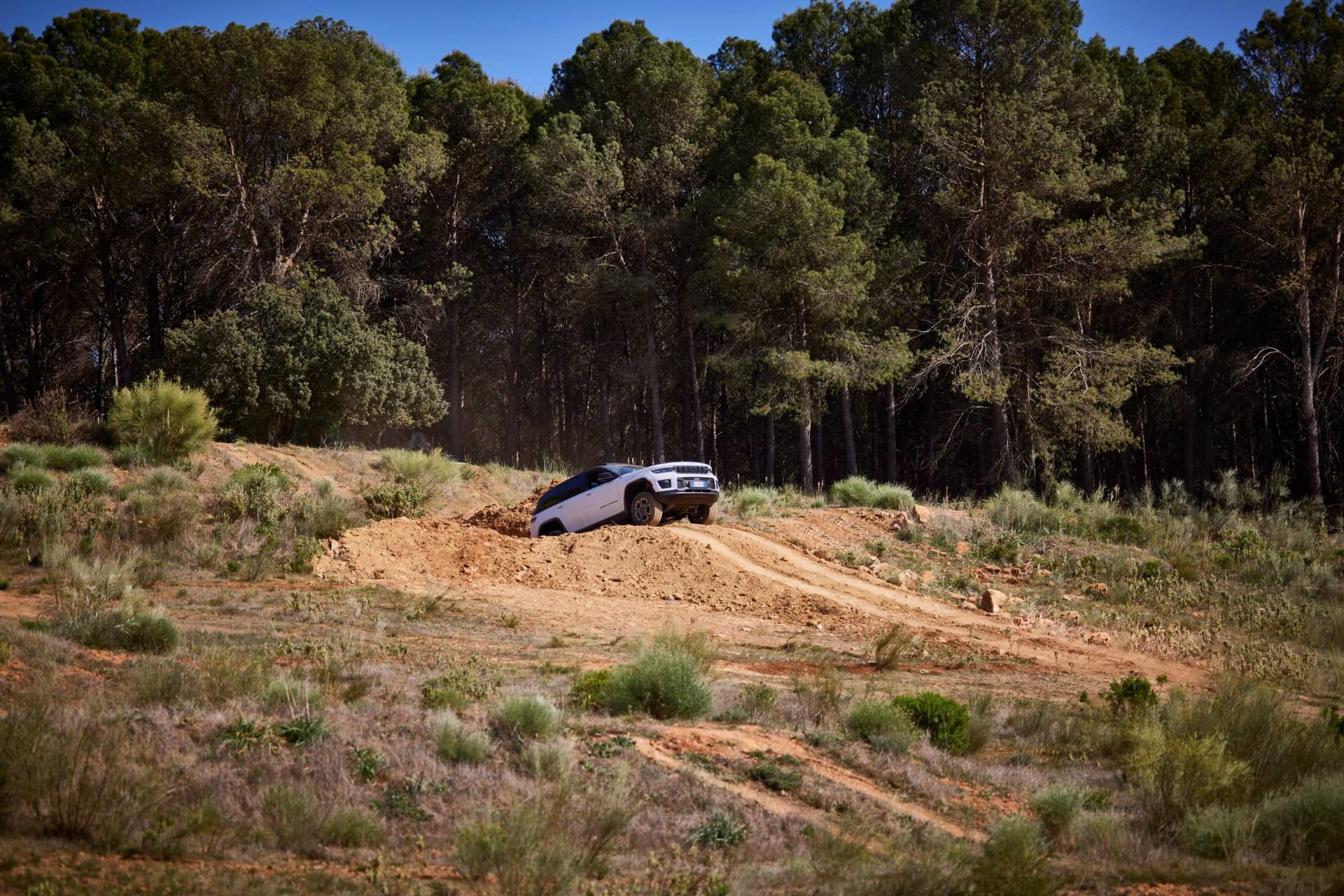 Jeep Grand Cherokee superando terreno accidentado en un sendero boscoso.