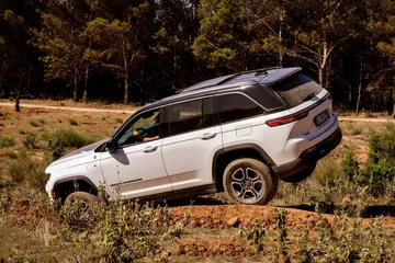 Vista lateral del Jeep Grand Cherokee en acción, destacando su capacidad todoterreno