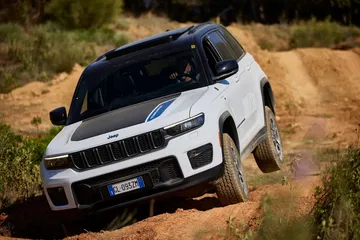 Vista dinámica del Jeep Grand Cherokee dominando terreno accidentado.
