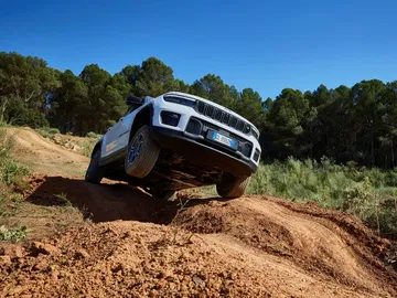 Vista lateral del Jeep Grand Cherokee superando obstáculo en terreno accidentado