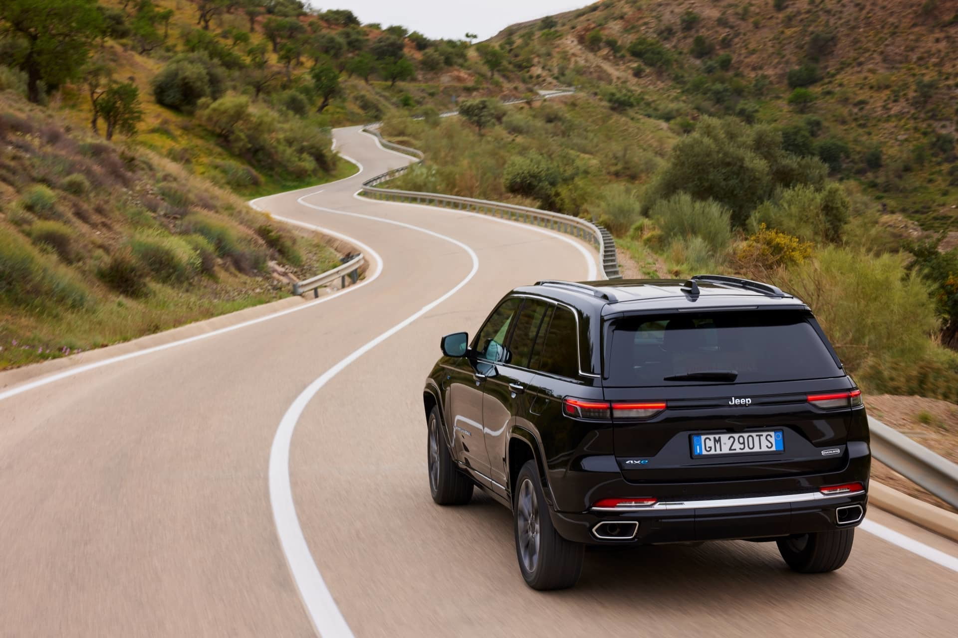 Vista dinámica de la trasera y lateral del Jeep Grand Cherokee en carretera.