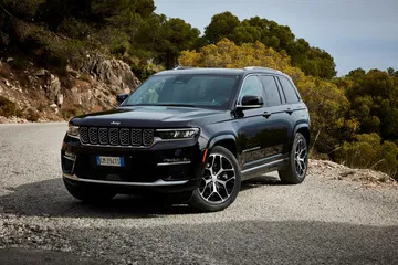Jeep Grand Cherokee mostrando un ángulo delantero y lateral en terreno pedregoso.