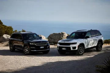 Dos Jeep Grand Cherokee aparcados frente al mar, vista delantera lateral.