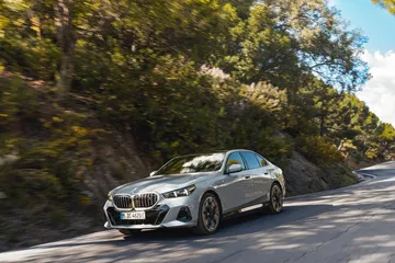 Vista dinámica del BMW Serie 5 en carretera de montaña, destacando su diseño y porte.