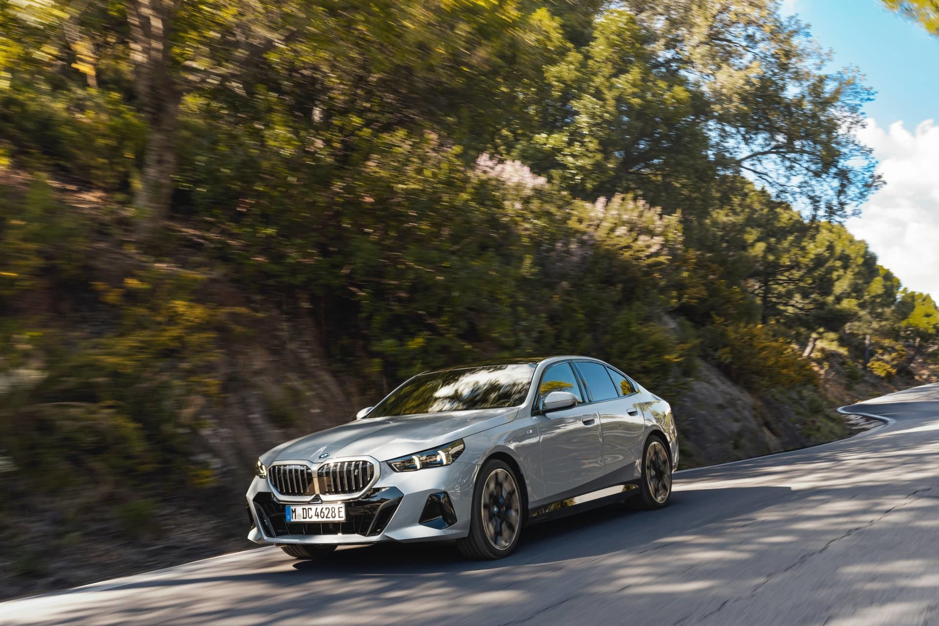 Vista dinámica del BMW Serie 5 en carretera de montaña, destacando su diseño y porte.