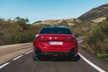 Vista trasera del BMW Serie 5 en movimiento, mostrando diseño de luces y parachoques.