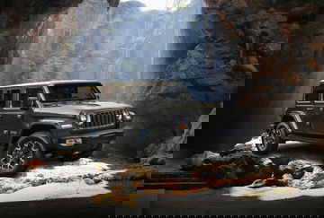 Vista lateral del Jeep Wrangler sobre terreno rocoso, destacando su capacidad off-road.