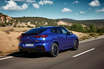 Perfil dinámico del BMW X2 en carretera, destacando su línea coupé.