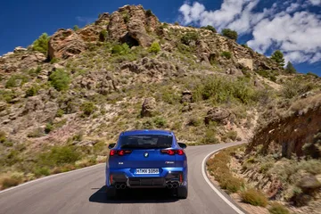 Vista dinámica del BMW X2 destacando su línea trasera y lateral en movimiento.
