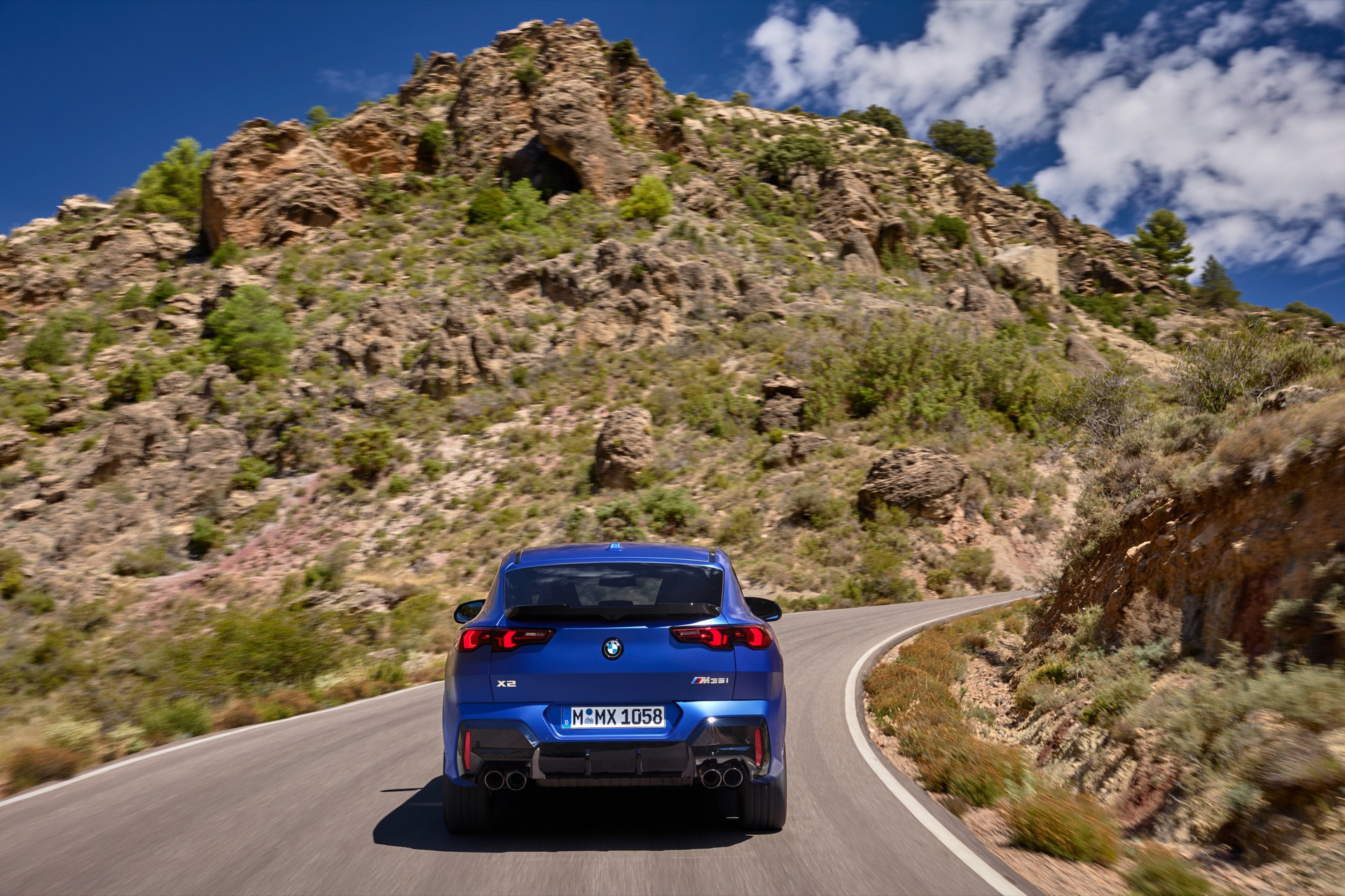 Vista dinámica del BMW X2 destacando su línea trasera y lateral en movimiento.