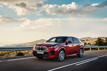 BMW X2 captado en movimiento mostrando su perfil lateral en carretera.