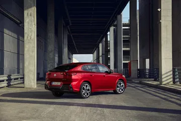 Vista dinámica del BMW X2 en ambiente urbano, destacando su diseño trasero y lateral.