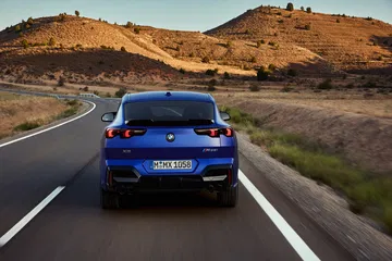 Vista trasera del BMW X2 en carretera, destacando su diseño deportivo.