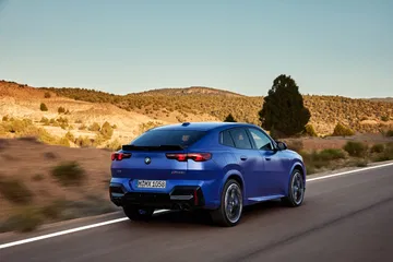 Vista dinámica del BMW X2 en movimiento, destacando su línea trasera y lateral.