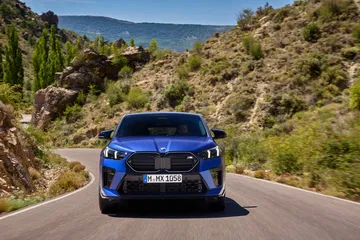 Vista frontal del BMW X2 rodando por carretera serpenteante.