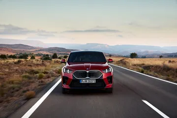 Vista trasera del BMW X2 resaltando su diseño deportivo en carretera.