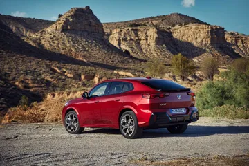 BMW X2 mostrando su diseño trasero y líneas laterales deportivas.