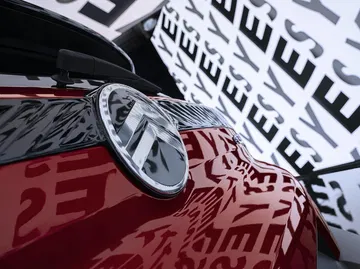 Vista cercana del emblema de Citroën sobre el capó del C3 reflejando edificios urbanos.