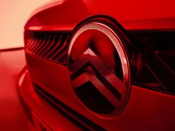 Primer plano del emblema de Citroën en un C3 rojo, destacando su diseño icónico.