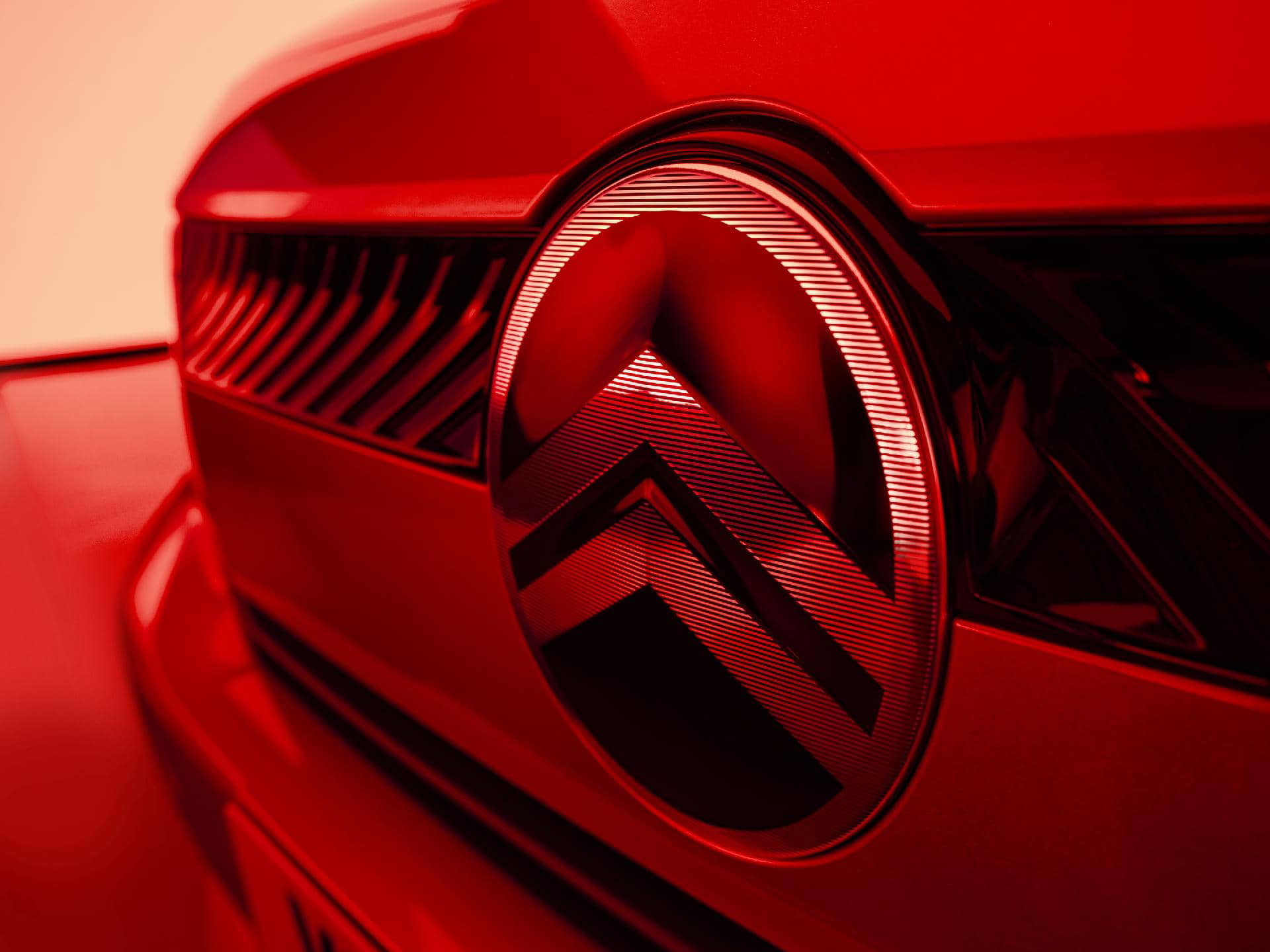 Primer plano del emblema de Citroën en un C3 rojo, destacando su diseño icónico.