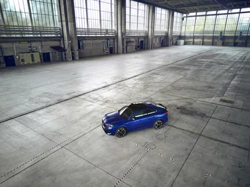 Vista lateral del BMW X2 en una nave industrial, destacando su diseño aerodinámico.