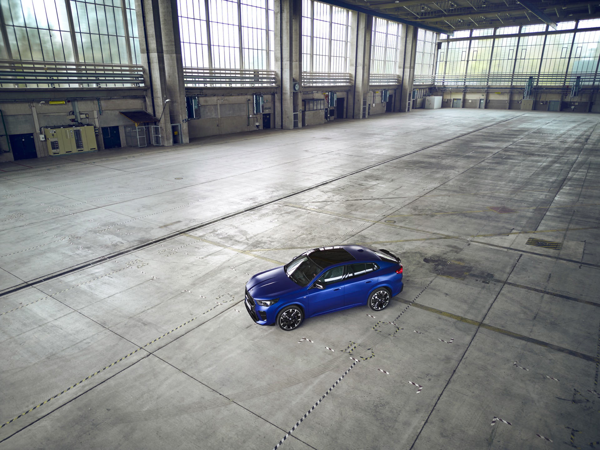 Vista lateral del BMW X2 en una nave industrial, destacando su diseño aerodinámico.