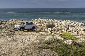 Vista lateral de un Dacia Duster en un entorno natural, resaltando su perfil todo terreno.