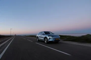 Vista lateral del BYD Seal U circulando por una carretera al atardecer.