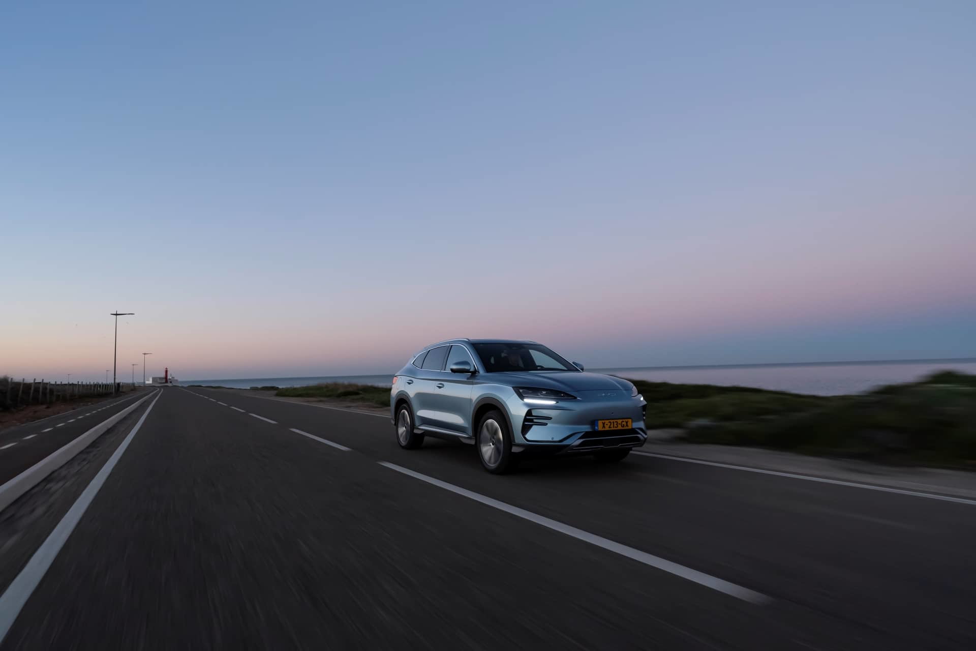 Vista lateral del BYD Seal U circulando por una carretera al atardecer.