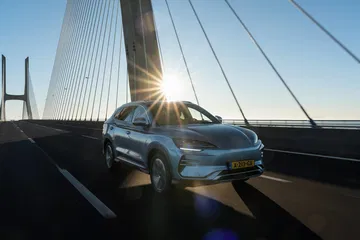 Vista lateral del BYD Seal U cruzando un puente al atardecer.