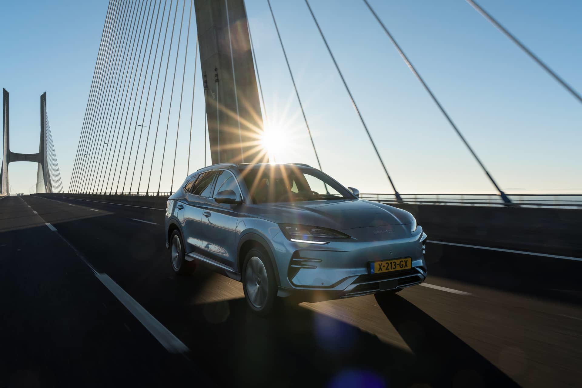 Vista lateral del BYD Seal U cruzando un puente al atardecer.