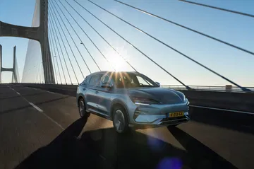 BYD Seal U avanzando por un puente al atardecer, vista delantera y lateral.