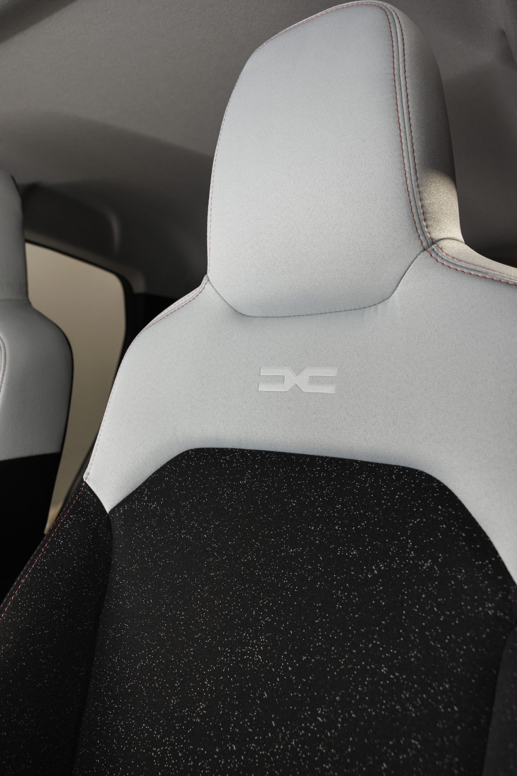 Vista cercana del detalle del asiento con el distintivo 'DC' del Dacia Spring.