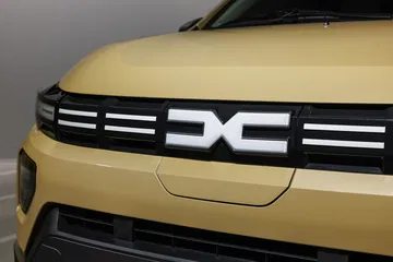 Vista cercana del frontal destacando el emblema y diseño de luces del Dacia Spring.