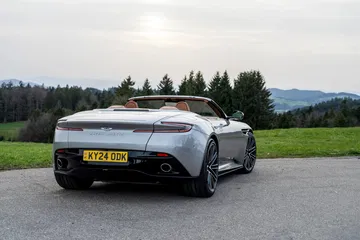 Vista trasera lateral del Aston Martin DB12 Volante, destacando su diseño aerodinámico y elegante.